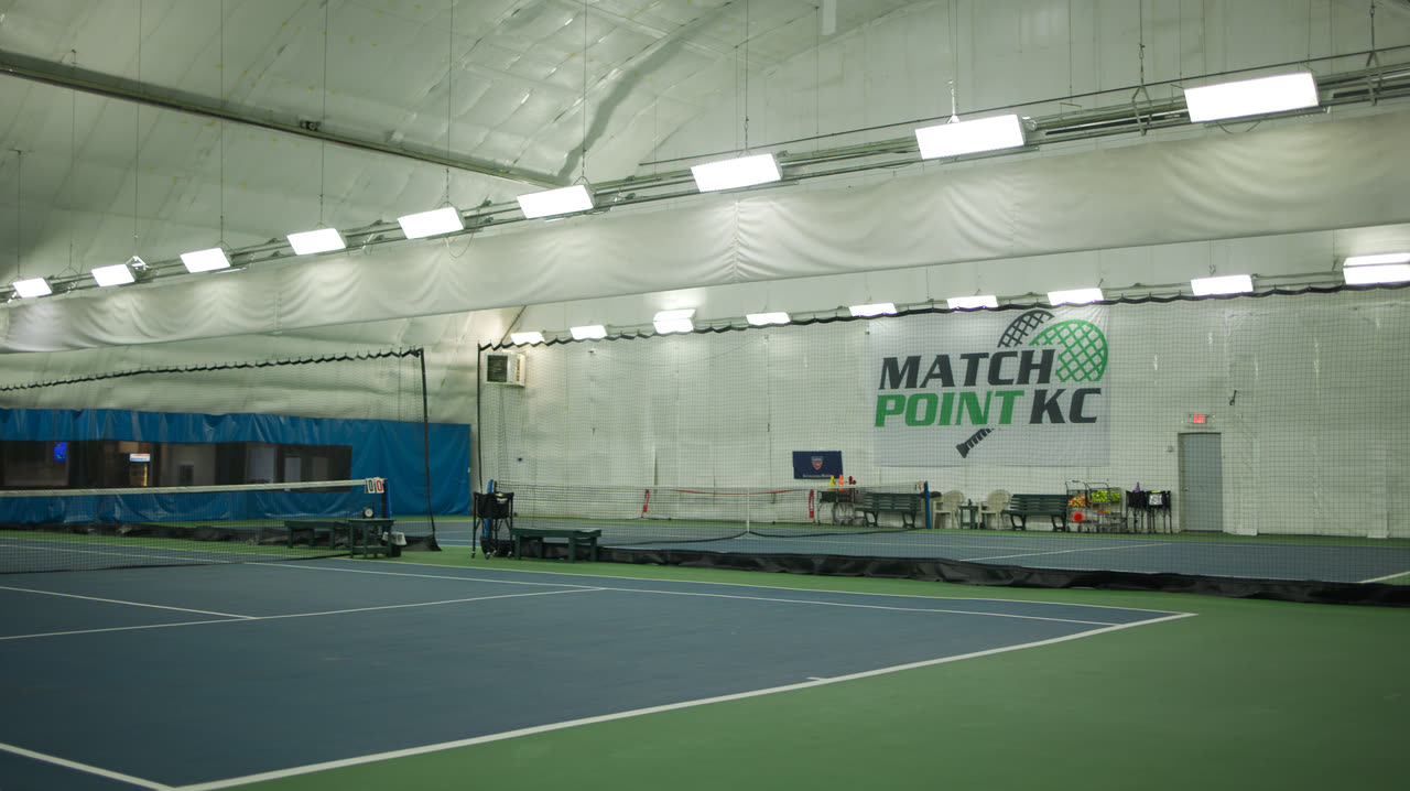 An indoor hard court at Match Point KC with the club banner on the wall