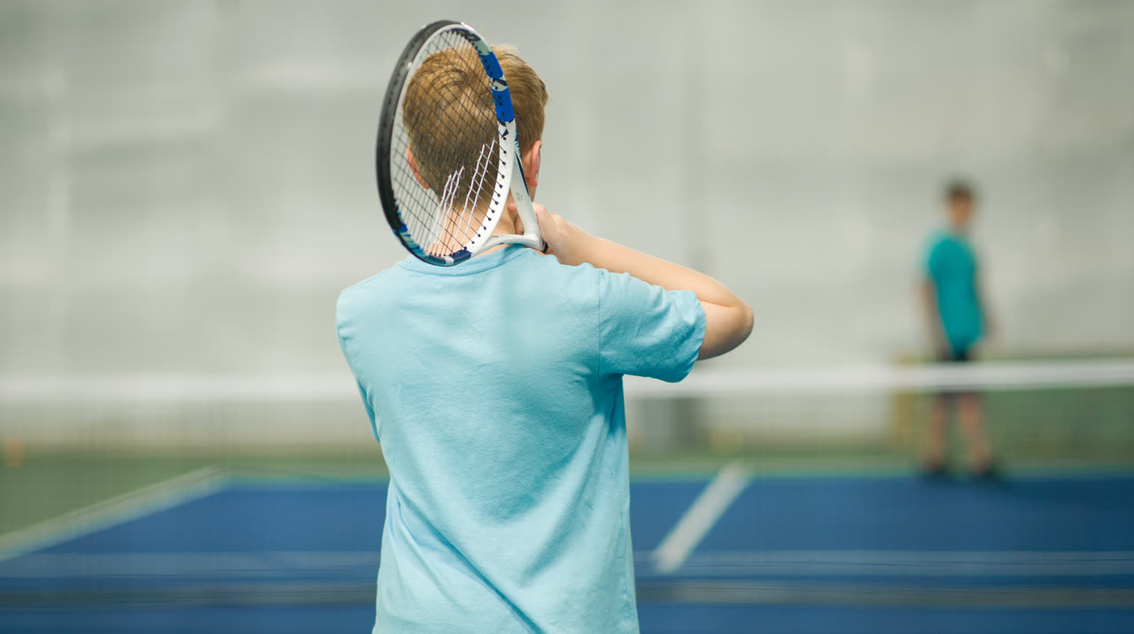 A junior player lining up a backswing during an indoor session at Match Point KC