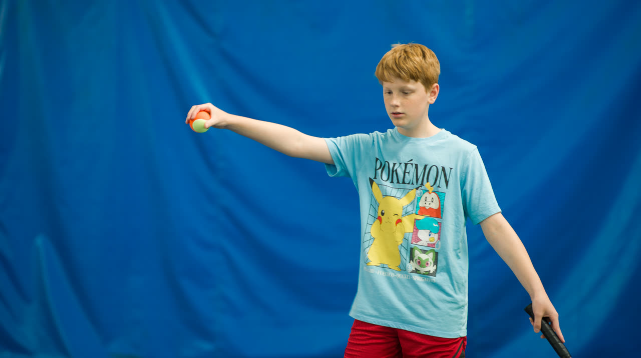 A junior player catching a ball during a drill at Match Point KC